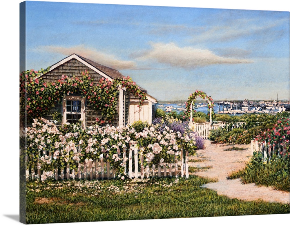 Beach front house with fenced rose garden and harbor boats in the background on a sunny day.