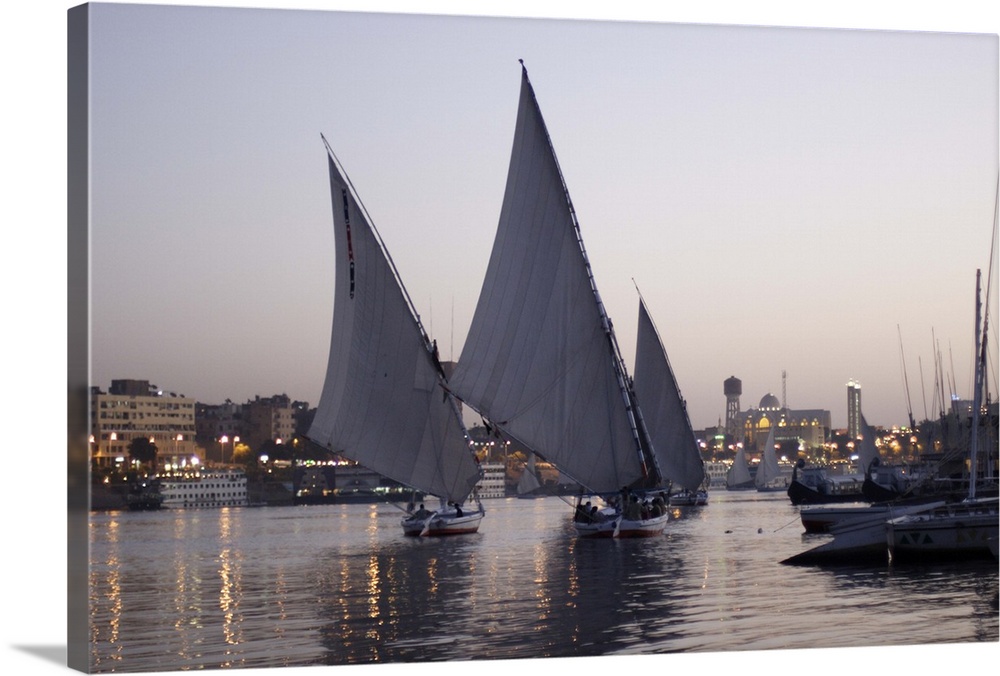 Aswan, skyline of the city in the background and 3 feluccas with big quadrangular sails