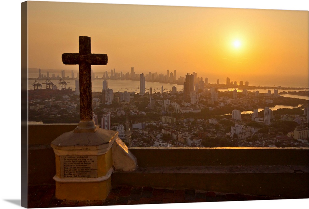 A cross with the Cartagena skyline in the distance at sunset.
