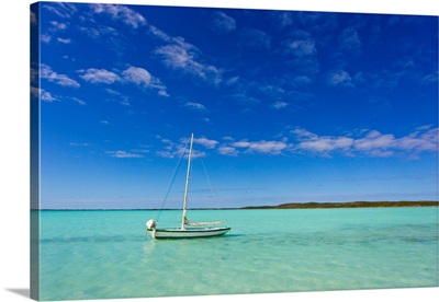 A lone sailboat anchored in turquoise water