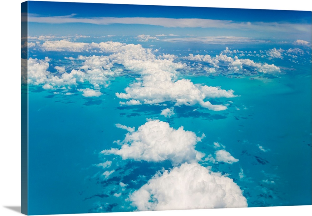 An aerial view above the clouds over the turquoise waters of the Caribbean Sea, near the Bahamas.