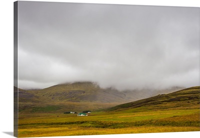 Low clouds cover the mountain tops surrounding a small ranch on Iceland