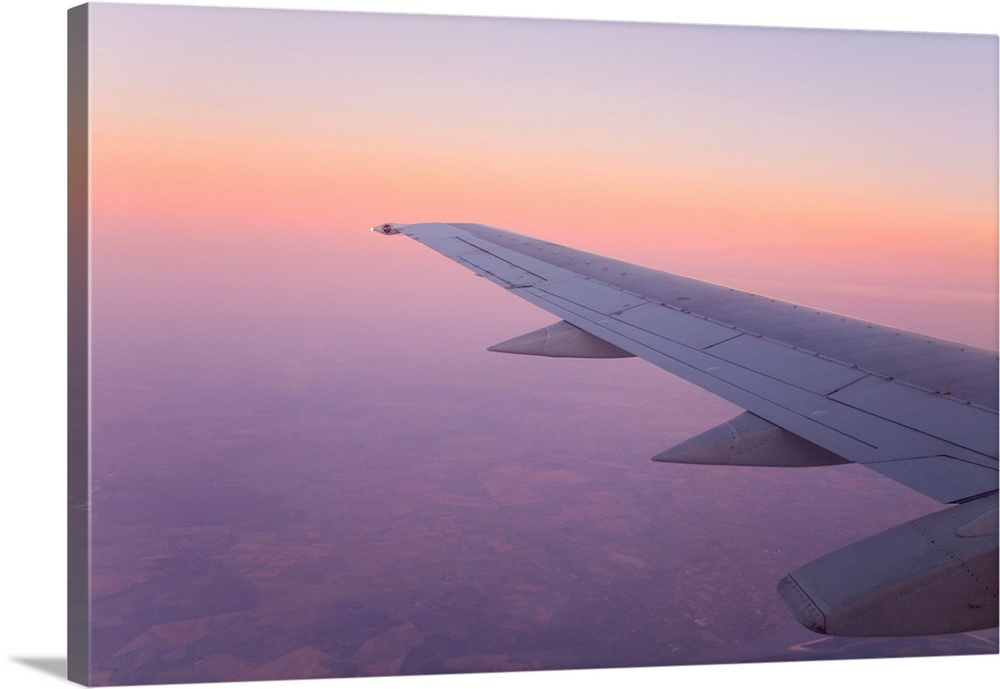 Looking out and airplane window at sunset with a purple sky.