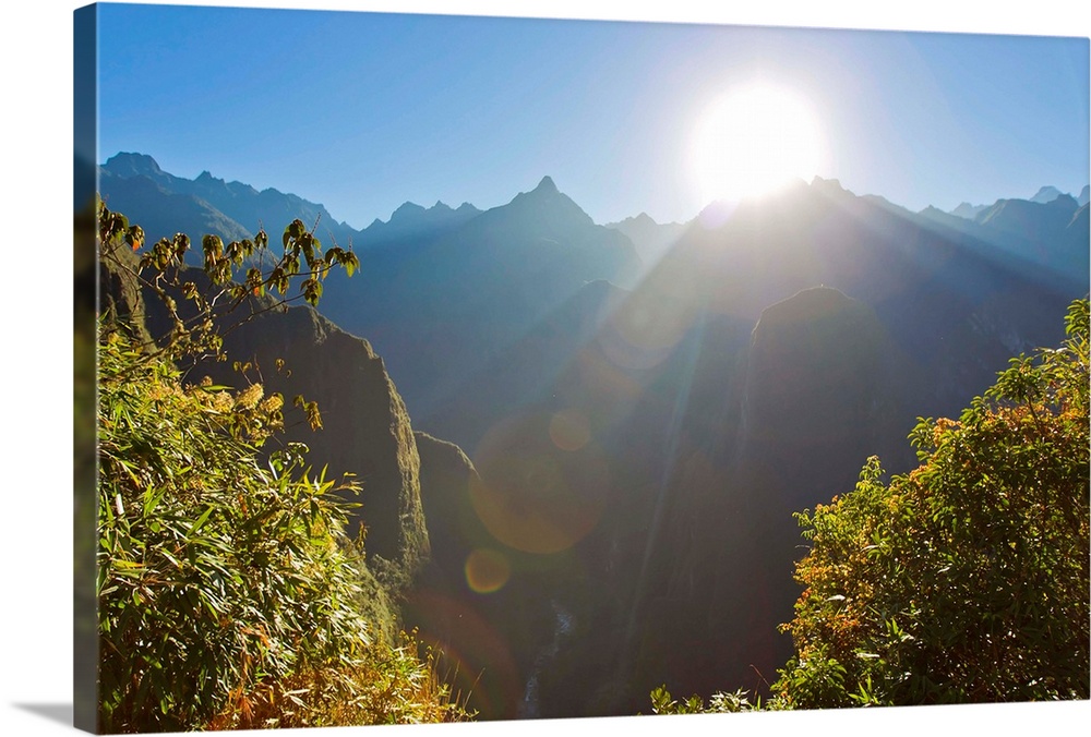 Rays of sun shine through gaps in the Andes mountains at Machu Picchu.