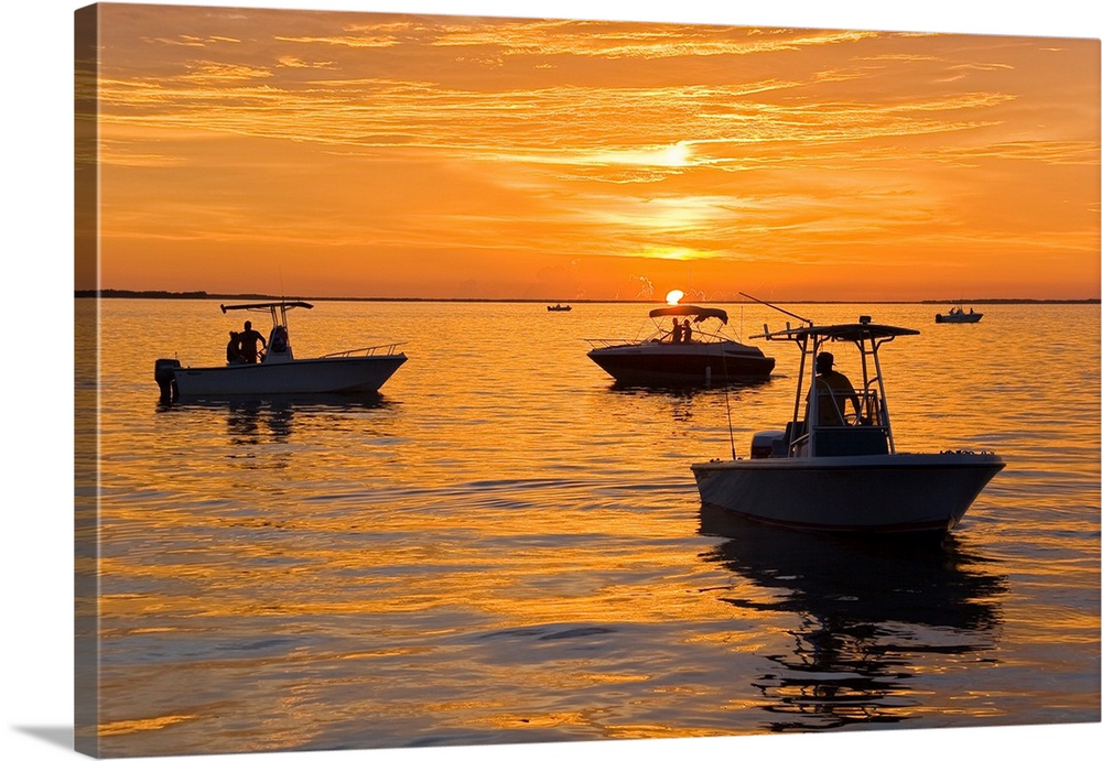 Silhouetted boats and shimmering water during a picture perfect sunset.