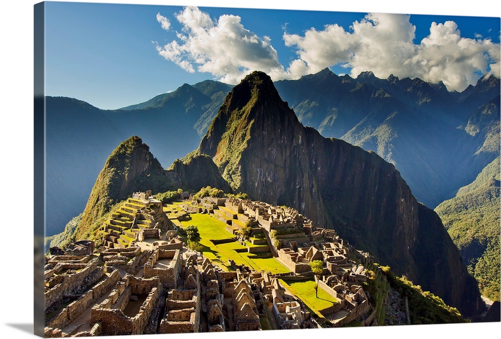 Sun shining through the Andes mountains onto Machu Picchu at sunset.