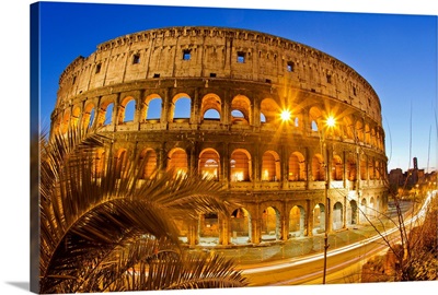 The ancient Roman Colosseum casts an illuminated golden light at dusk