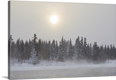 The sun glowing through thick clouds in subzero temperatures along the Yukon River