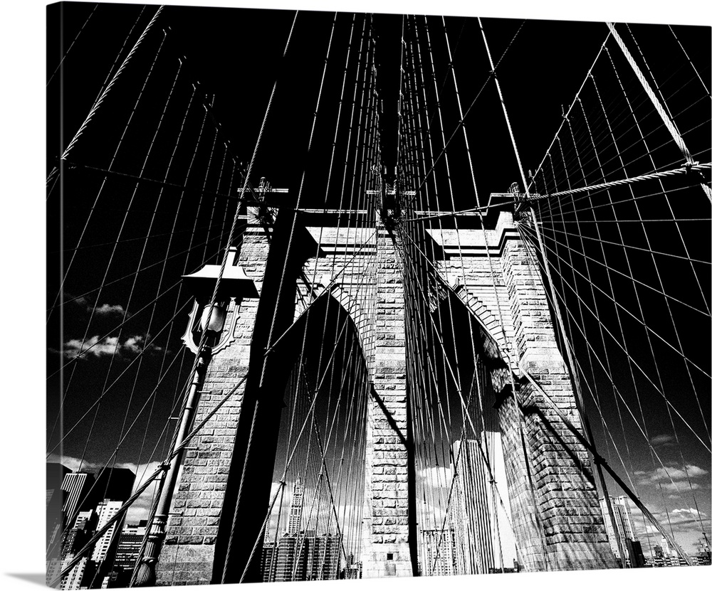 Dramatic black and white photograph of the Brooklyn bridge arches and suspension cables.