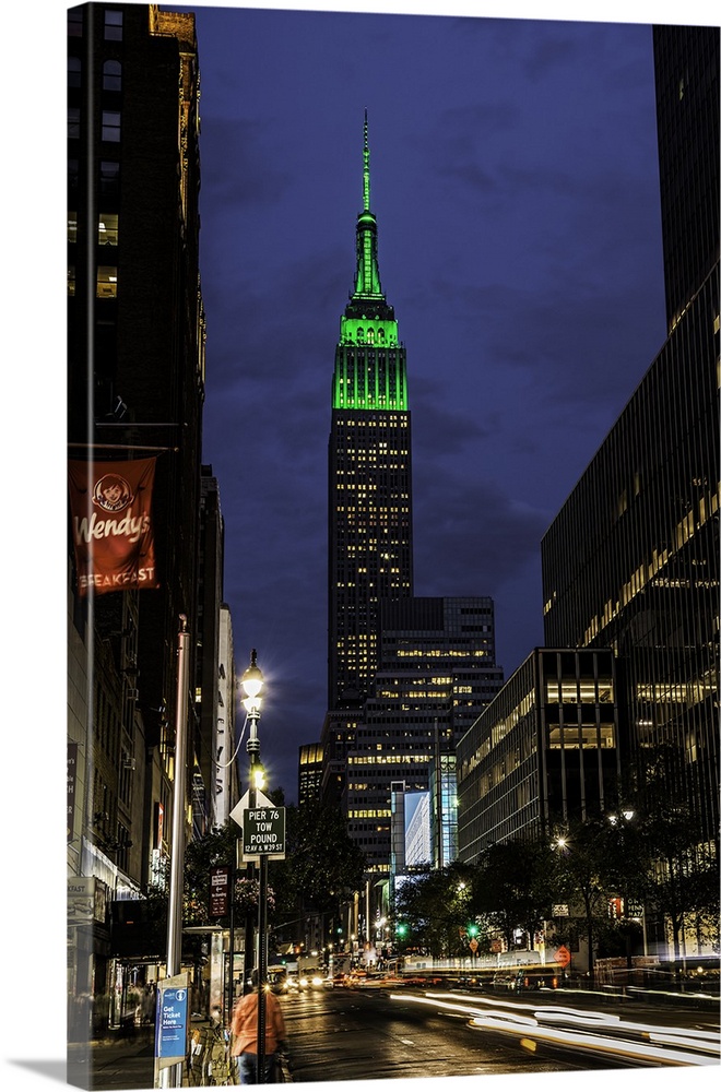 A photograph of the Empire State Building with a green top at sunset.