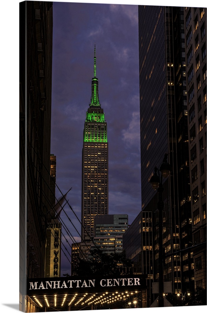 A photograph of the Empire State Building with a green top at sunset.