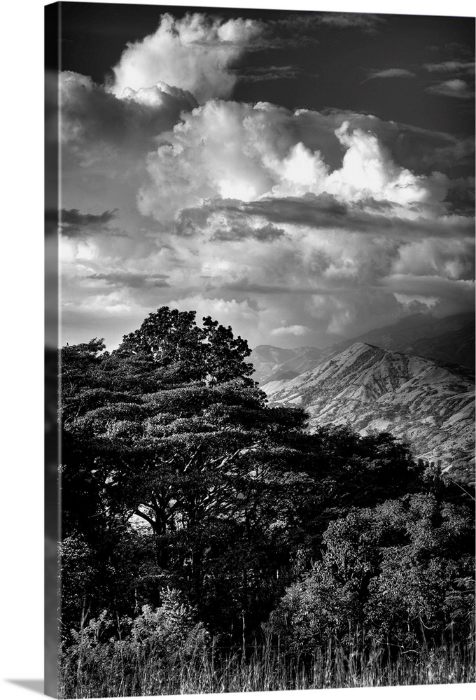 Black and white photograph of dramatic clouds hanging over a mountain peak.