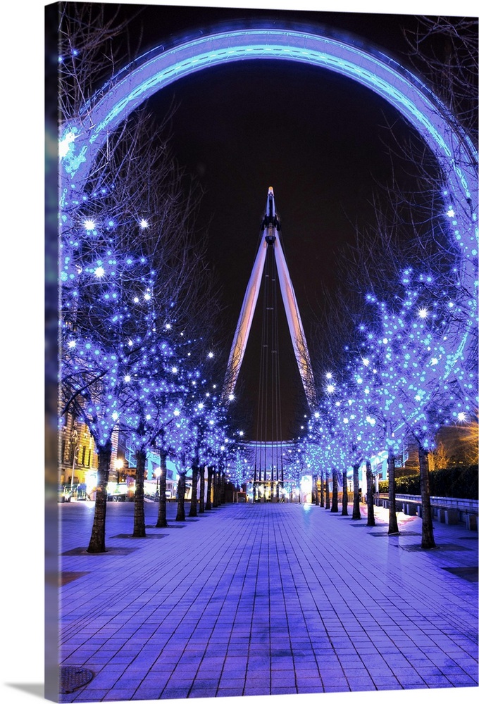 A photograph of the London Eye from a long aisle of blue lit up trees for Christmas.
