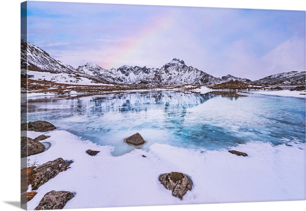 Frozen lake in the mountains with a rainbow
