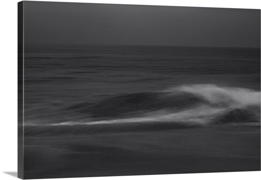Waves crashing on the shore in a silent lament on a cloudy dark evening.