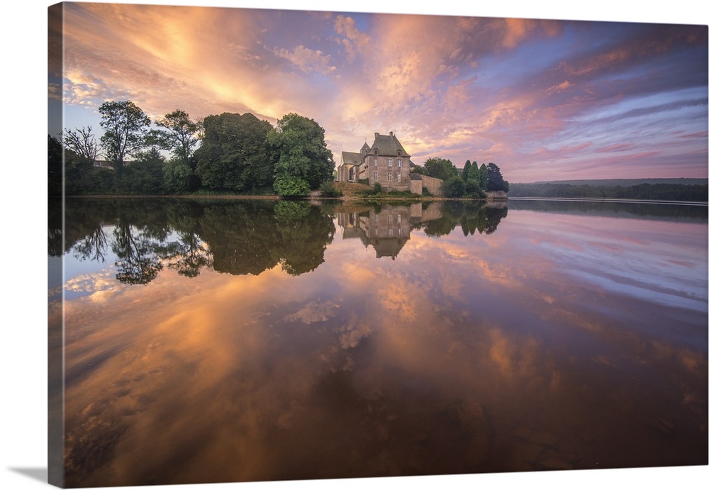 Abbey on the French coast under a pastel sunset sky reflected in the water.