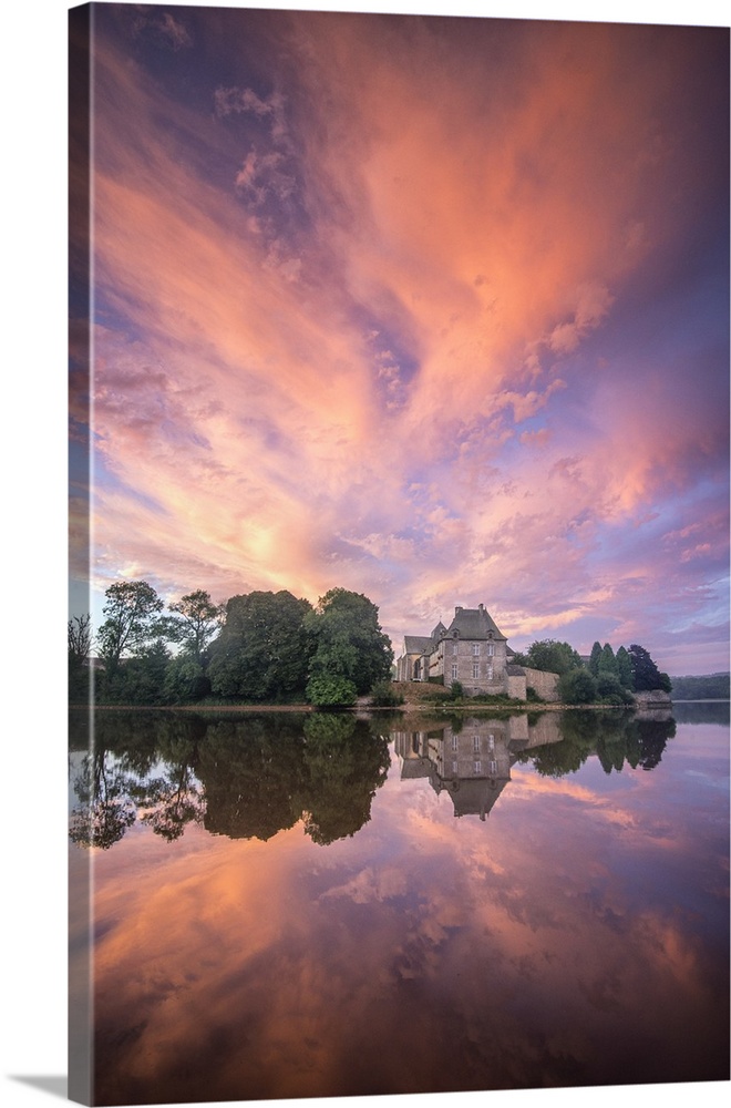 Fiery sunset clouds over a church, reflected in water.
