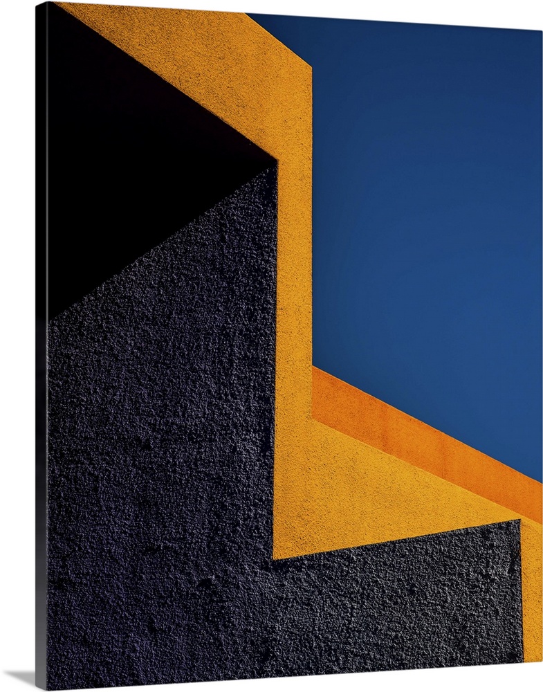 Grey and orange stucco walls in contrast against a deep blue sky.