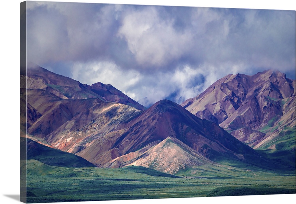 A beautiful dramatic sky hovers over grand Alaskan mountains and verdant valleys in this painterly landscape photograph.