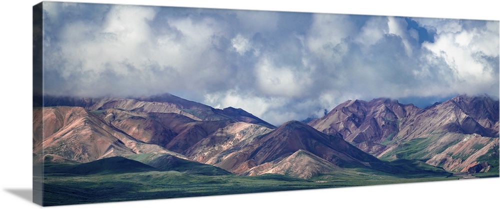 A beautiful dramatic sky hovers over grand Alaskan mountains and verdant valleys in this painterly panoramic photograph.