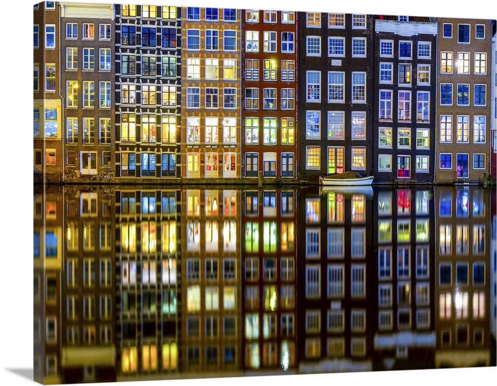 The historic center of Amsterdam with the interiors of the illuminated houses and the reflection of the buildings in the w...
