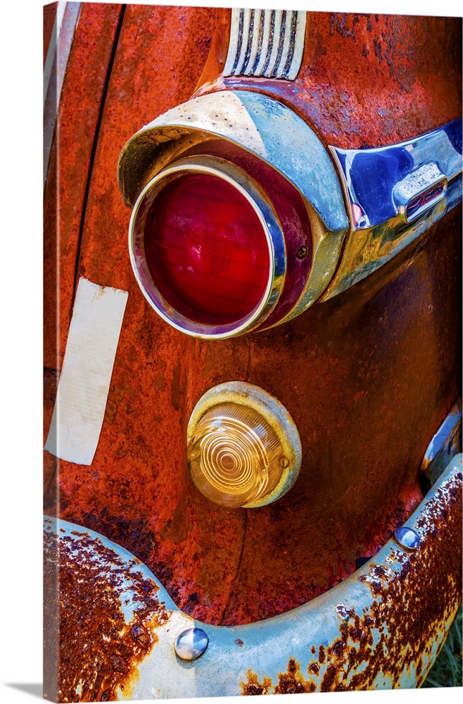 A vivid surrealistic rusty red antique Pontiac tail light section with red and yellow lenses and blue reflections in its c...