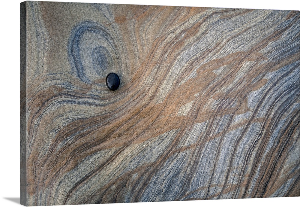 Photograph of a smooth black stone on top of a larger rock.