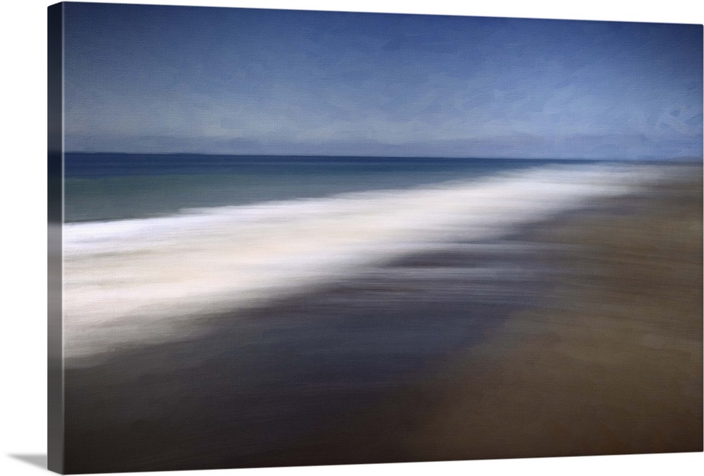 Blurred long-exposure image of the foamy sea on a sandy beach, moving with the tide.