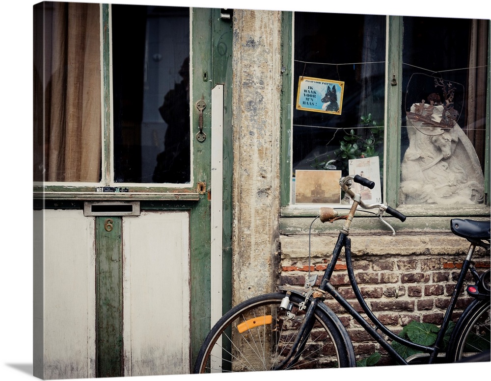 A photo of an aged building with a bicycle and a beware of dog sign in dutch out front.