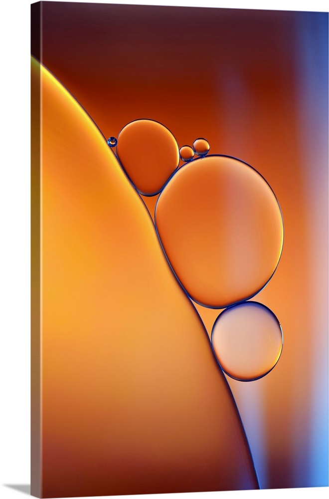 Closeup photograph of drops of oil in water with shades of orange and blue.