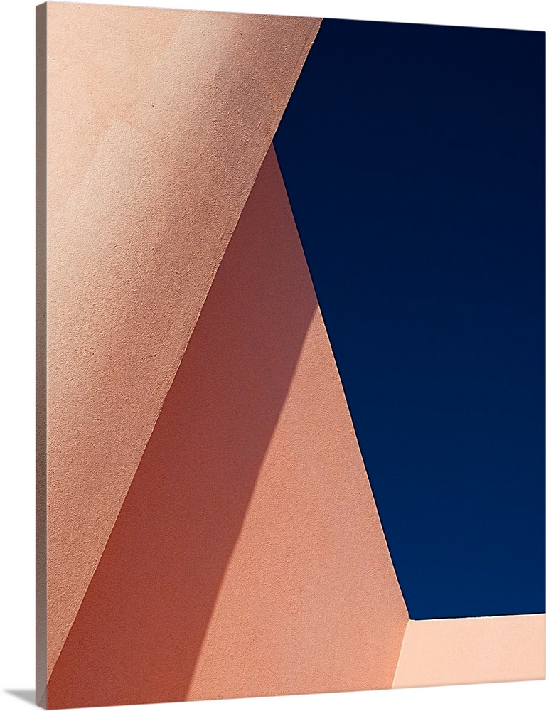 Abstract angle view of pale pink walls against a deep blue sky.
