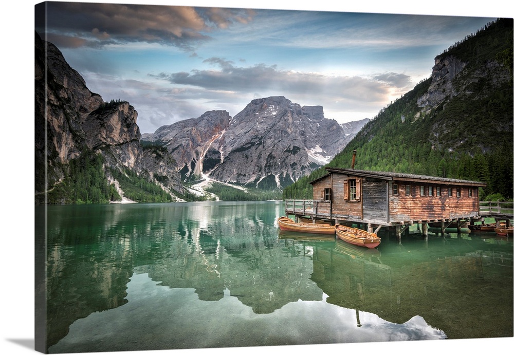 Jade green lake reflecting mountainous valley and cabin.