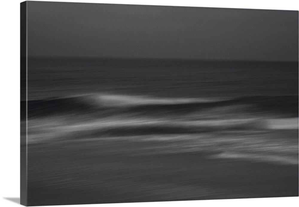 Waves crashing on the shore on a cloudy dark evening.
