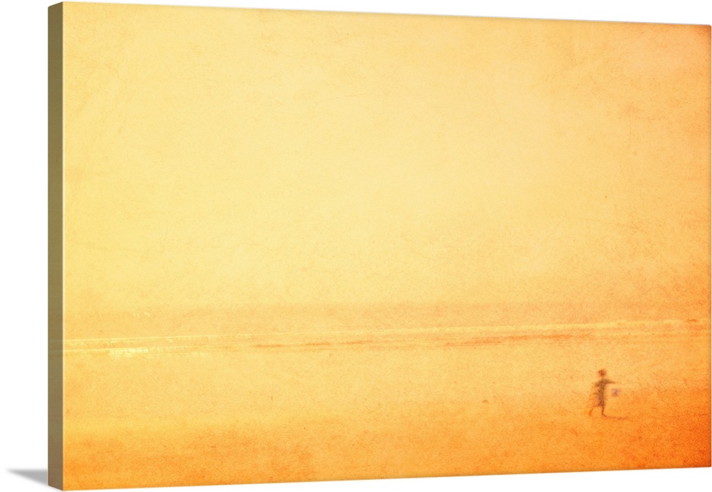 A dreamlike shimmering hazy yellow gold image of a child playing on a beach in the sun on holiday vacation.