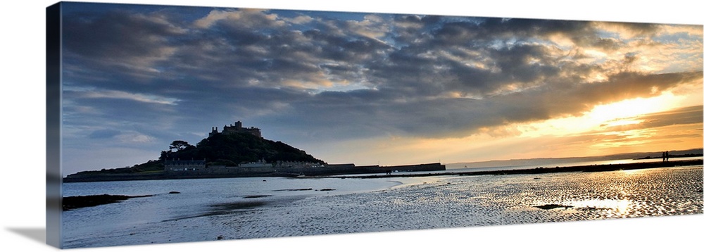 St. Michaels Mount, Cornwall, England, UK, at sunset with a dramatic sky and golden light reflected in wet rippled sand.