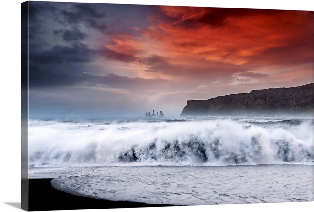 Photograph of a large crashing wave onto the shore with a bold red sunset above and a crescent moon to the left.