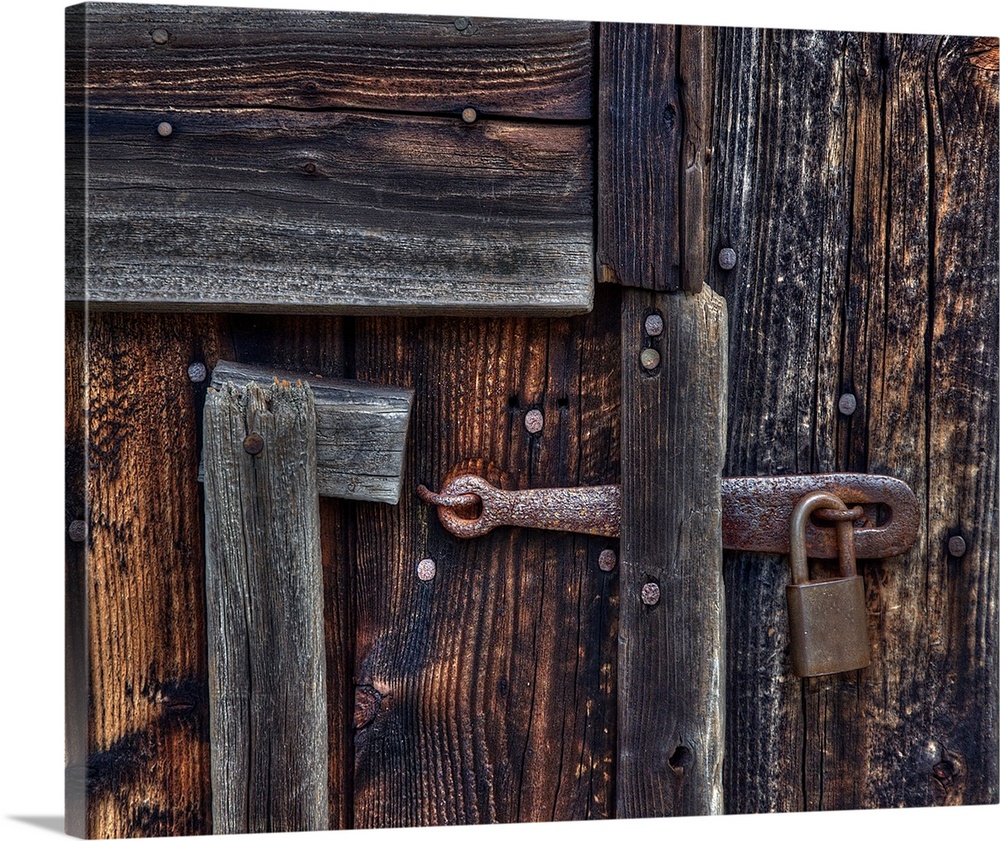Vintage metal lock on a wooden door full of nails.