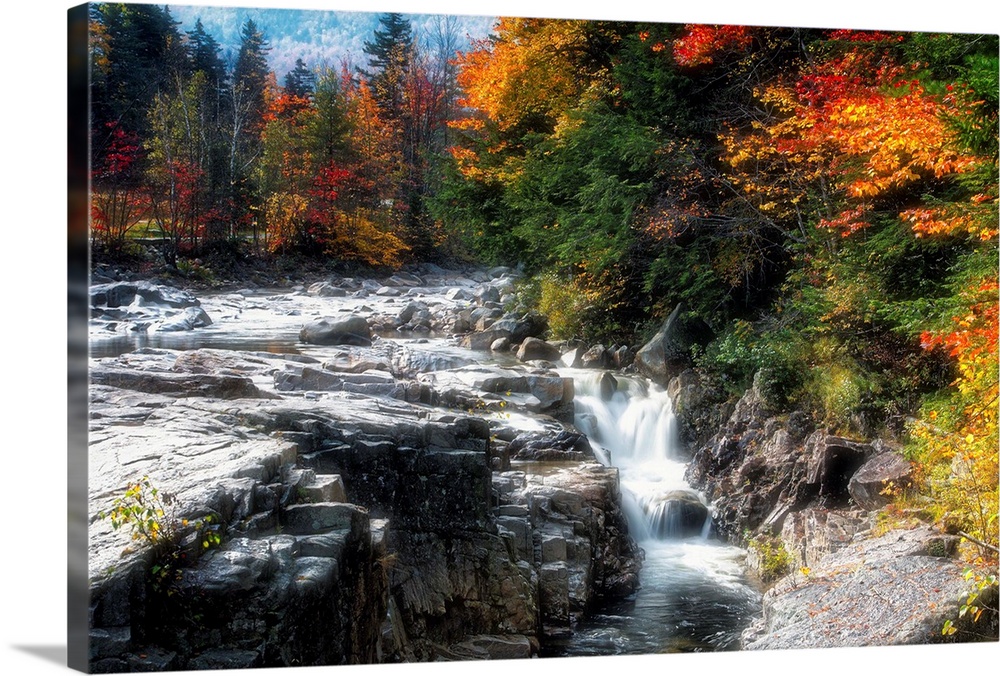Fine art photo of a rushing stream in a brightly colored forest in the fall.