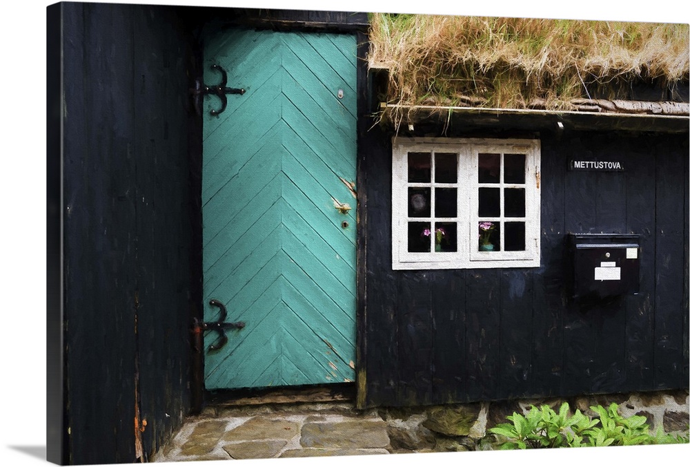 The side of a black house with a turquoise door and white window frames.