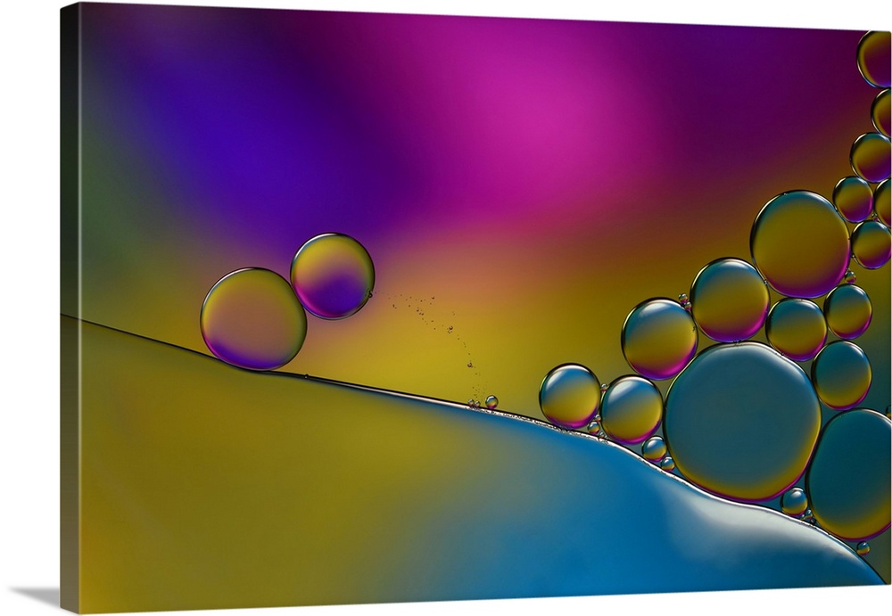 Abstract photograph of transparent droplets stacked together with blue, yellow, pink, and purple hues in in the background.