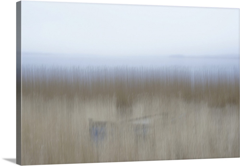 Artistically blurred photo. A rowing boat is hiding in the reed on the border of a lake.