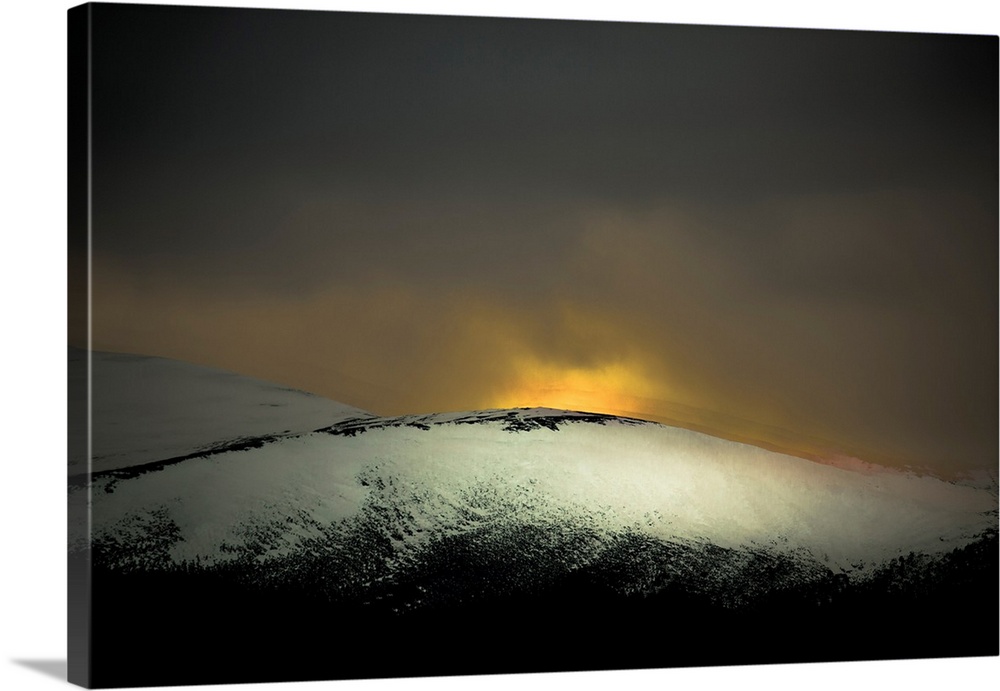A distressed photo a snow covered hill with dawn rising above it.