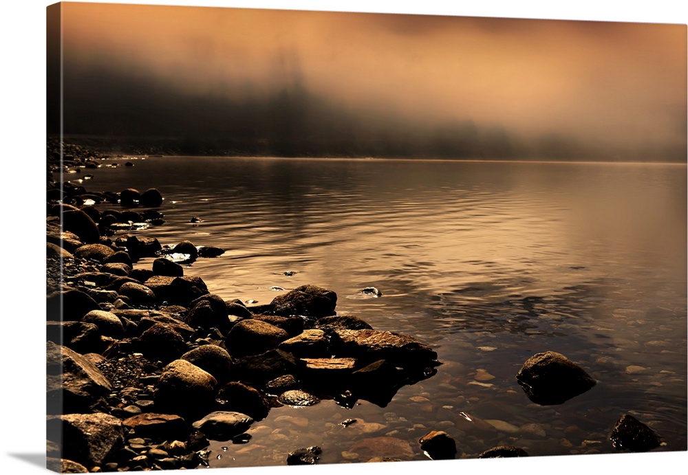 Landscape photograph of a rocky shore with orange fog covering the background.