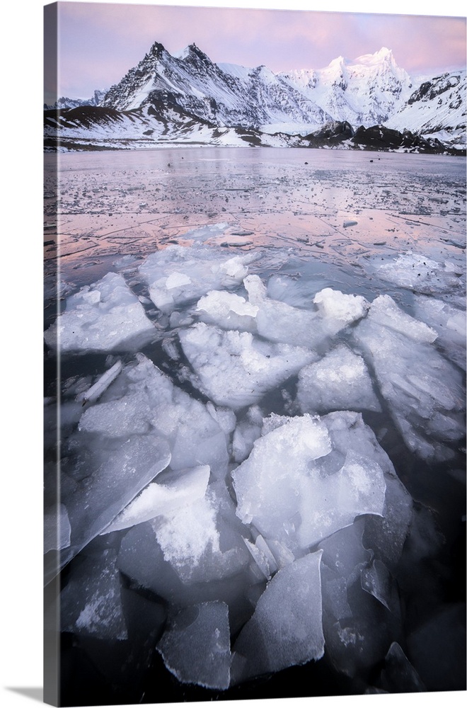 Sharp pieces of ice floating in the sea near dark mountains in Iceland.