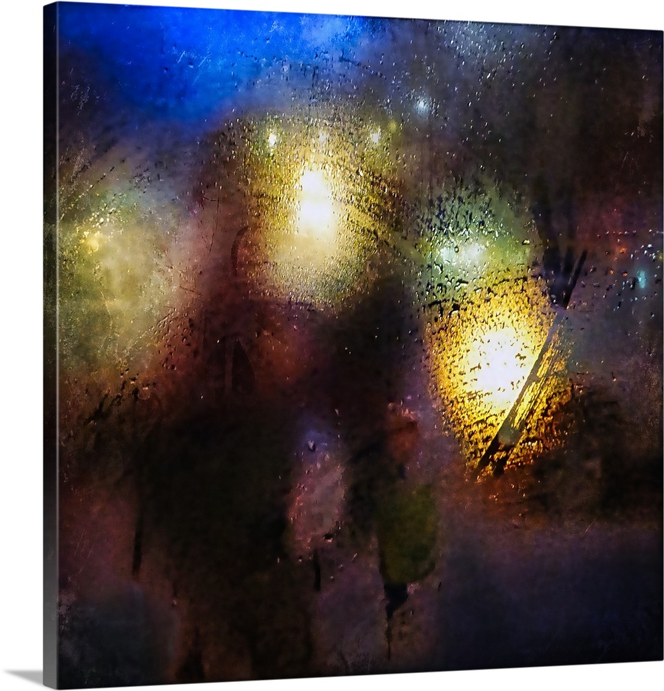 Abstract photograph of blurred street lights seen from behind a rain-covered window at night.