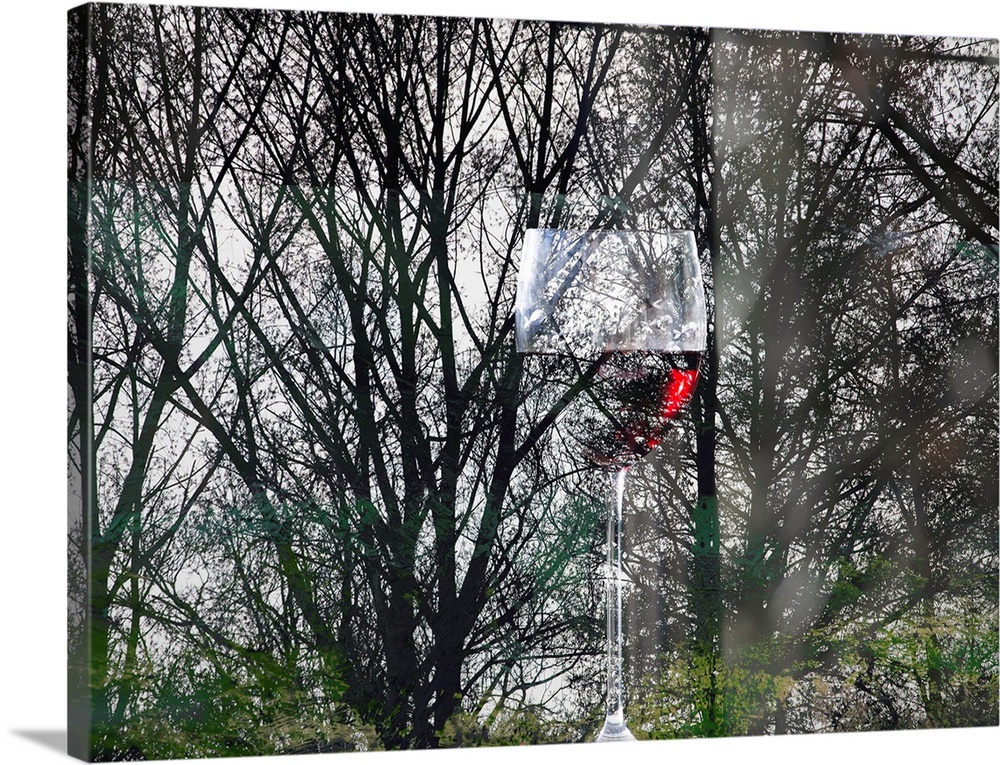 Conceptual photograph of a glass of red wine blending in with silhouetted forest trees with hints of green at the bottom.