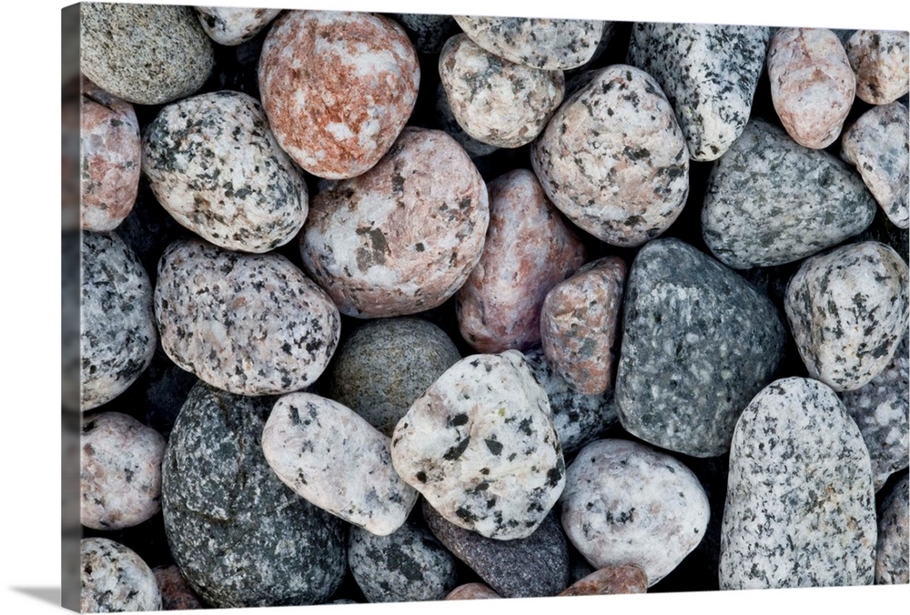 A close up of pale contemporary granite pebbles on a beach.