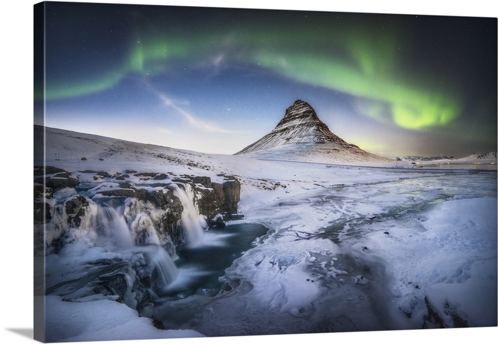 Waterfall and field below Kirkjufell in Iceland, with a green aurora borealis above.
