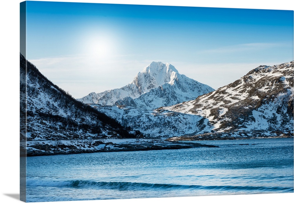A photograph of a mountain range seen from across a lake in winter.