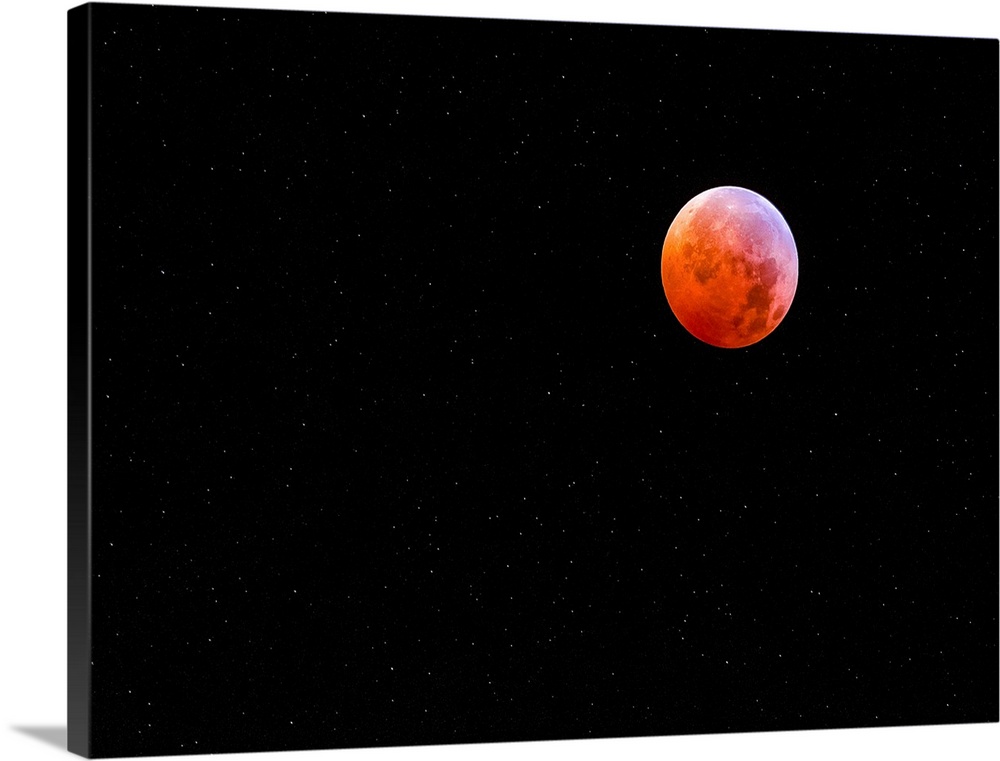 The moon in a starry night sky glowing bright red during an eclipse.